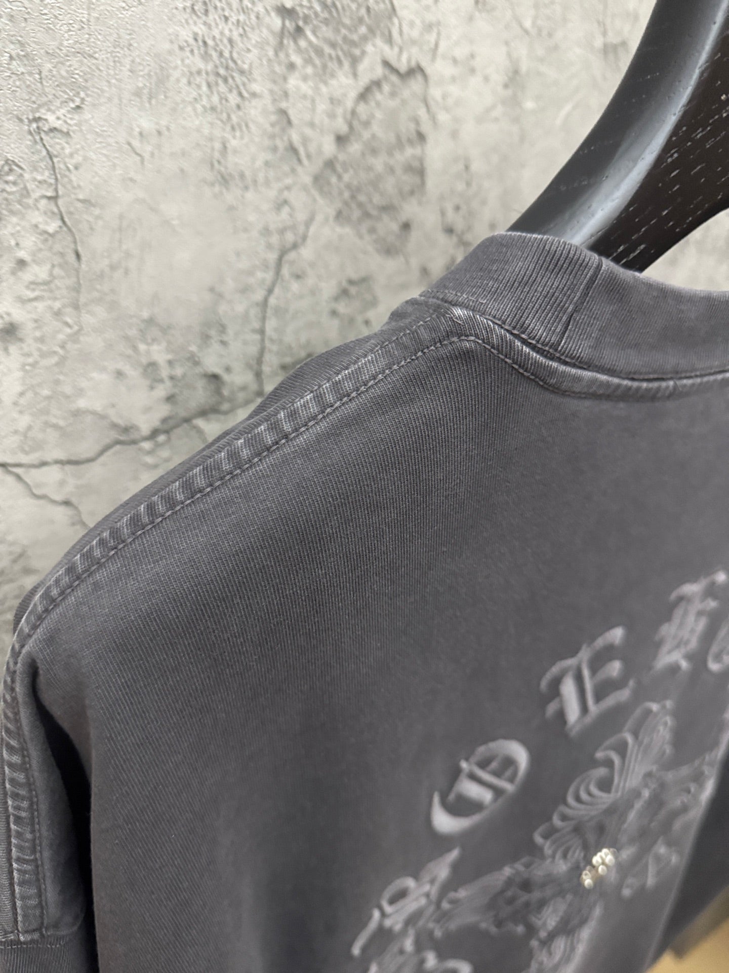 Dark gray T-shirt close-up of ribbed collar and embroidered side detail