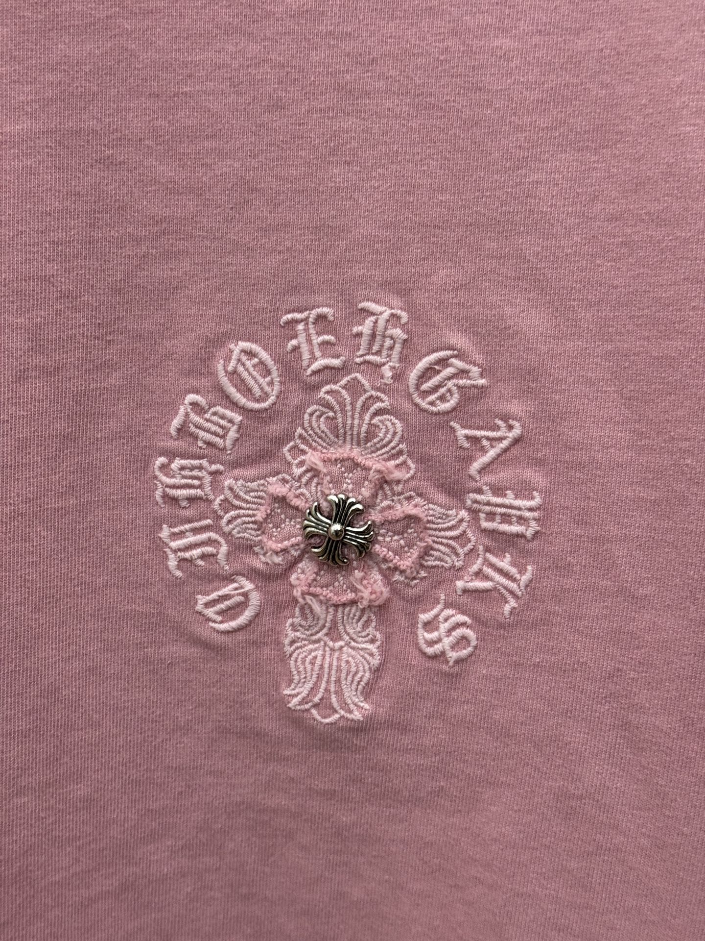Close-up of light pink T-shirt fabric with embroidered floral design