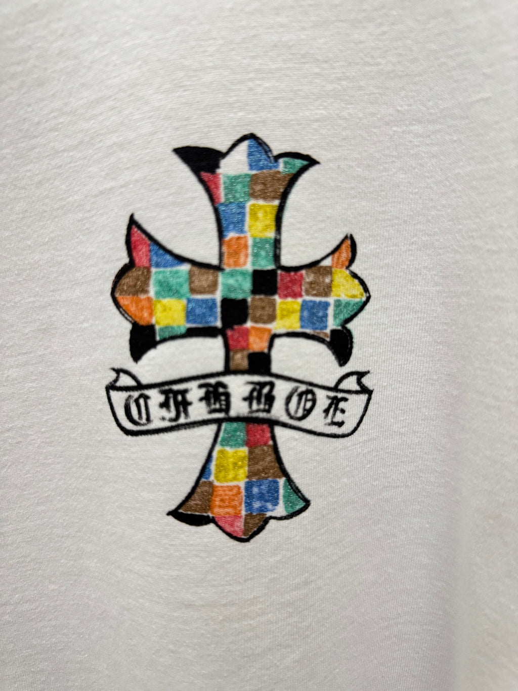 Close-up of white graphic T-shirt with colorful cross and banner print