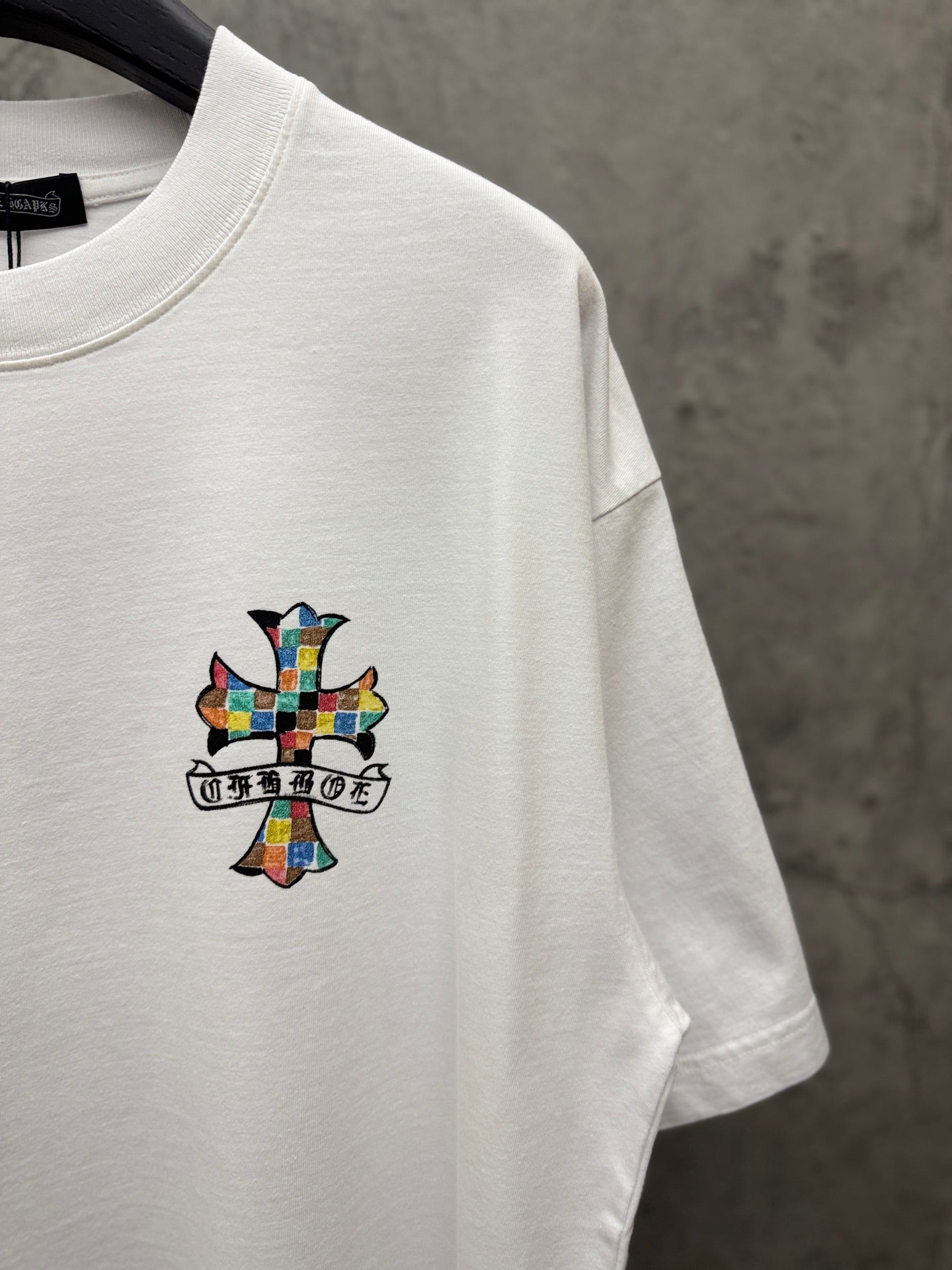 White crewneck T-shirt with small colorful cross graphic on the chest