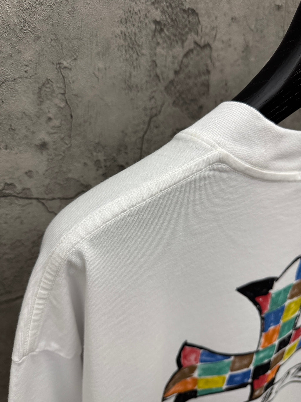 White T-shirt shoulder and sleeve with partial colorful cross graphic