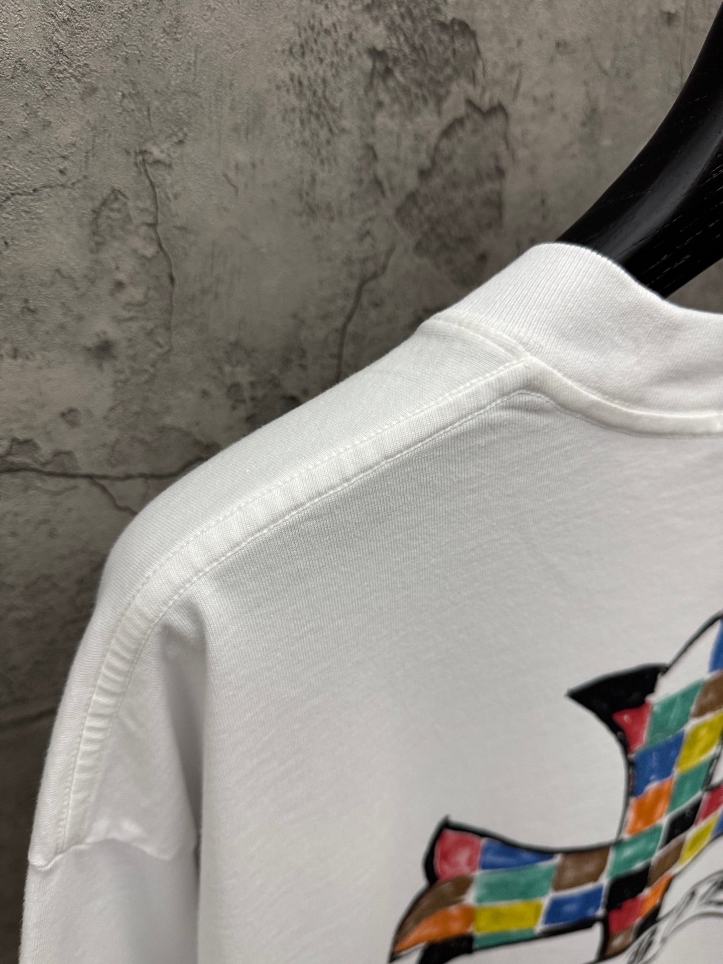 White T-shirt shoulder and sleeve with partial colorful cross graphic