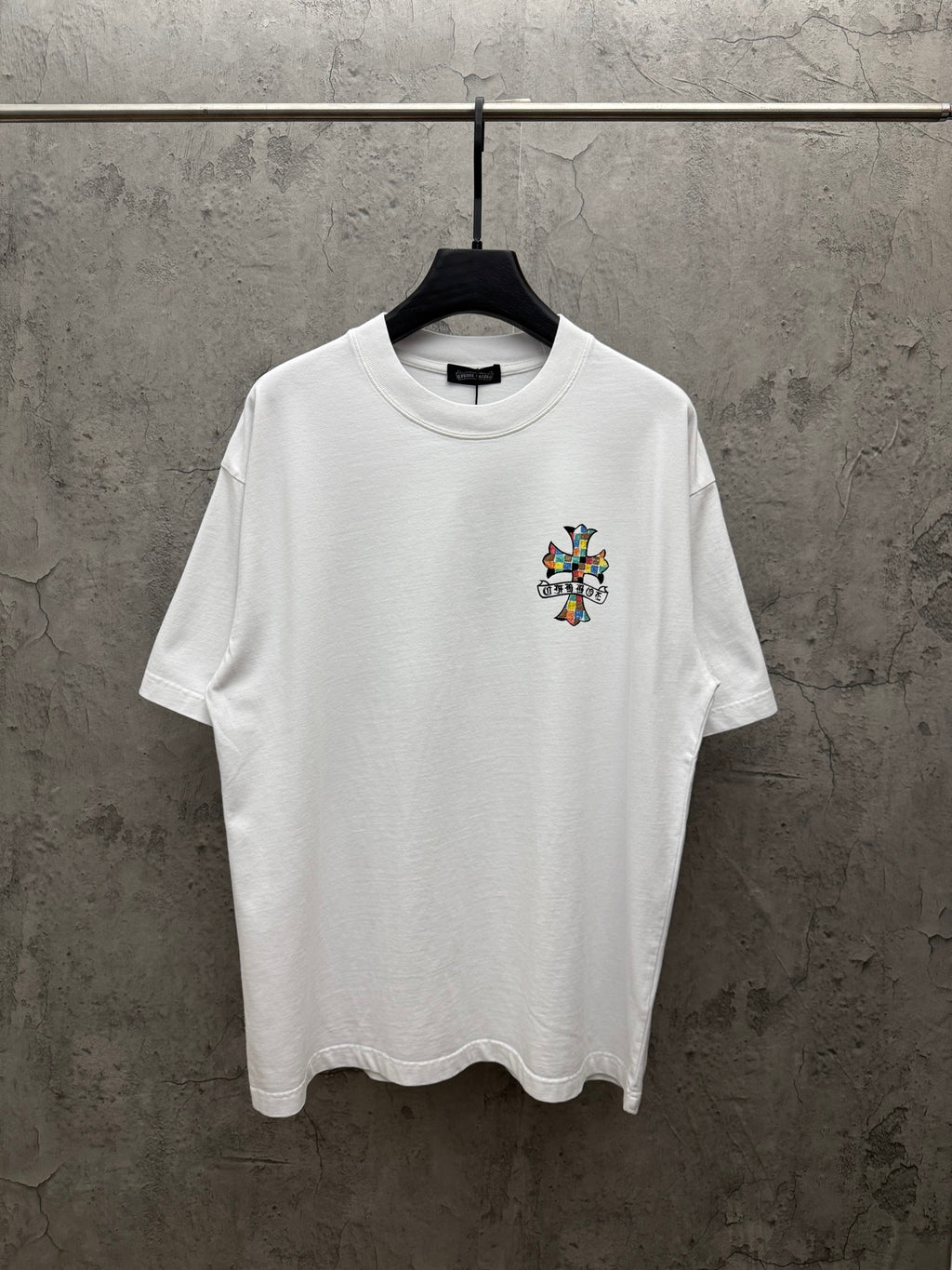 White crewneck T-shirt with small colorful cross graphic on the chest