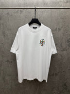 White crewneck T-shirt with small colorful cross graphic on the chest