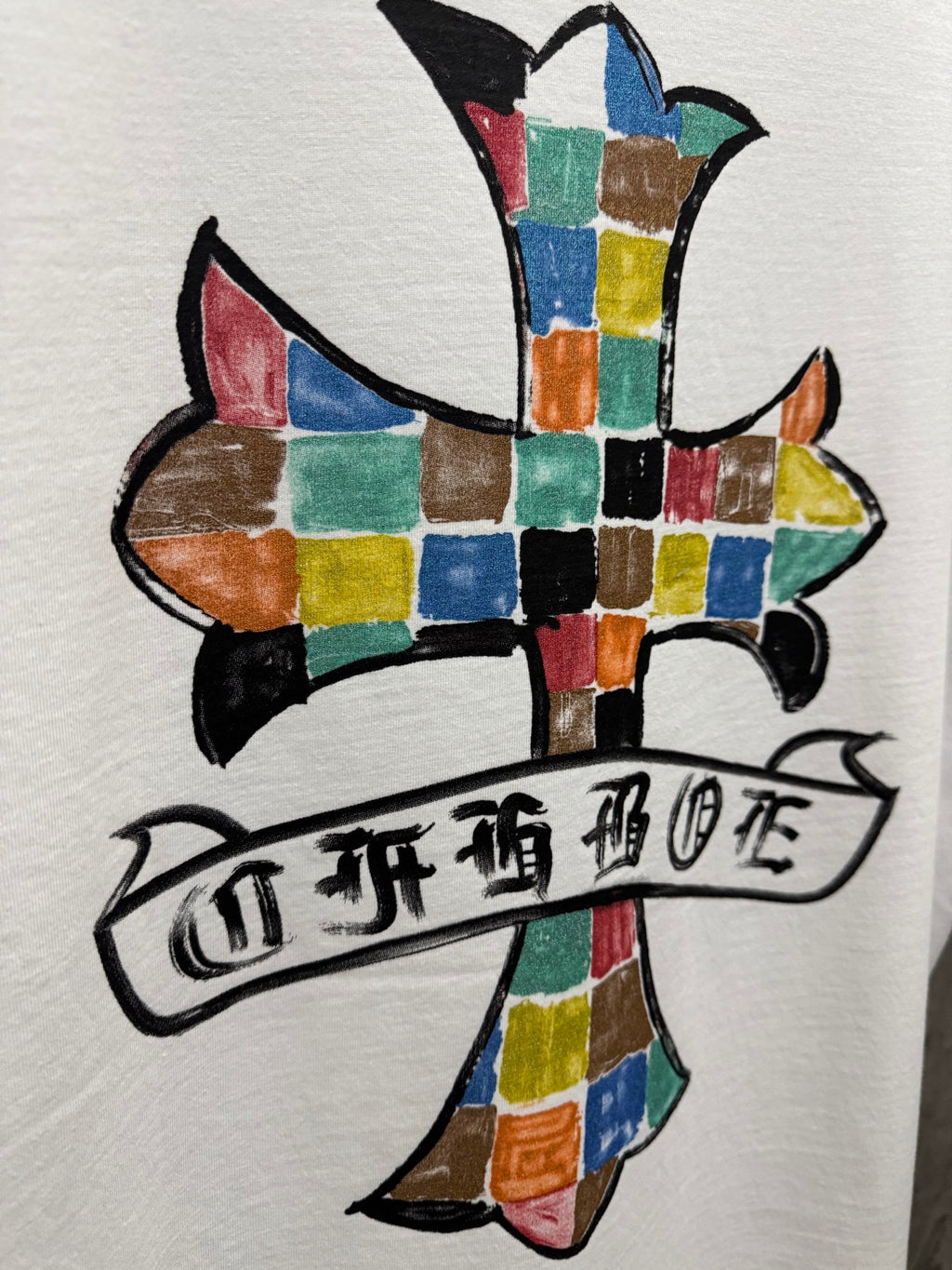 Close-up white crewneck T-shirt with colorful cross graphic and banner
