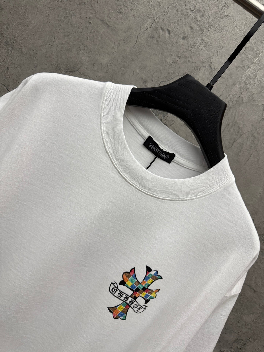 White crewneck T-shirt with ribbed collar and small colorful cross graphic