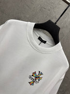White crewneck T-shirt with ribbed collar and small colorful cross graphic
