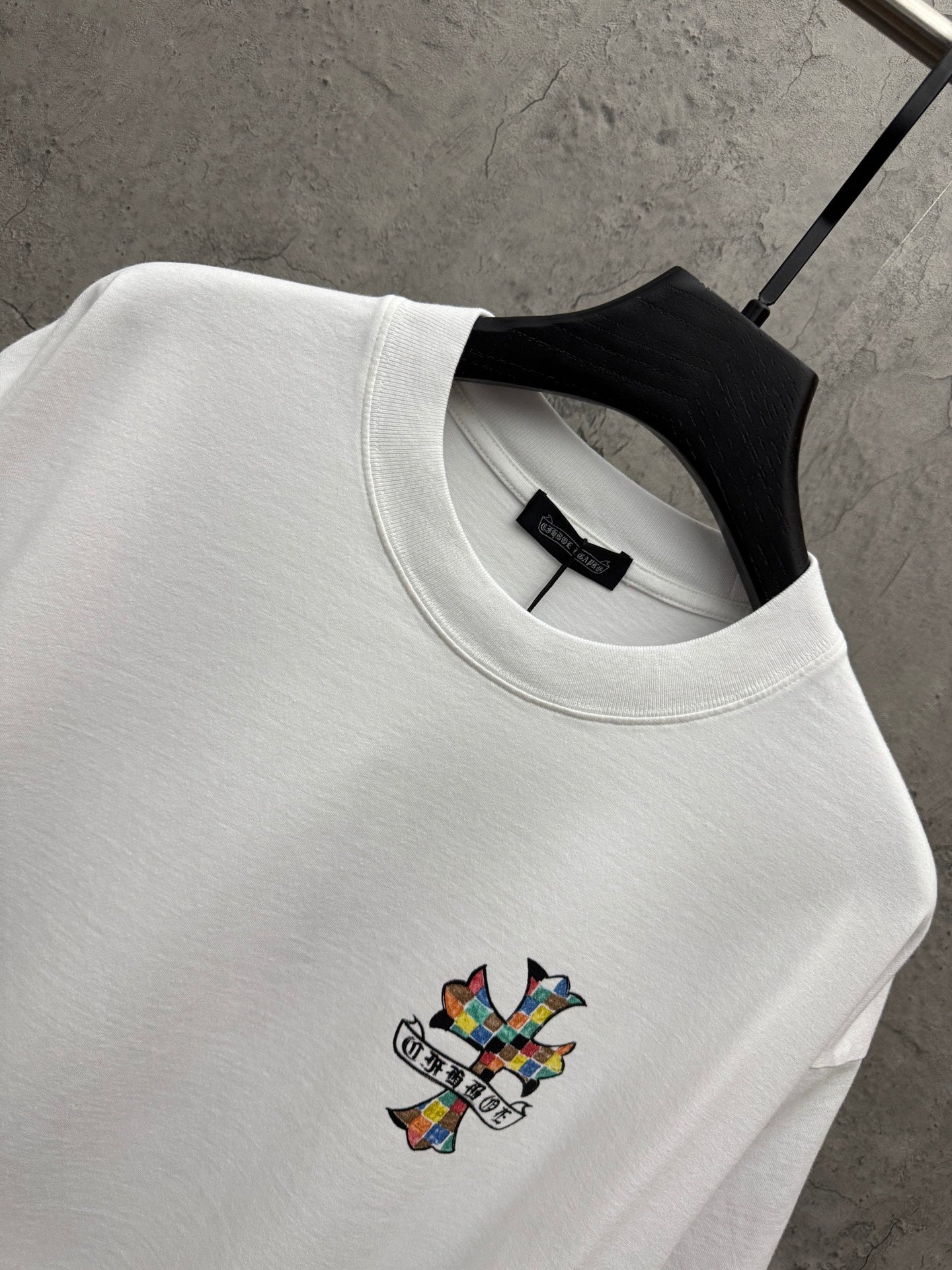 White crewneck T-shirt with ribbed collar and small colorful cross graphic