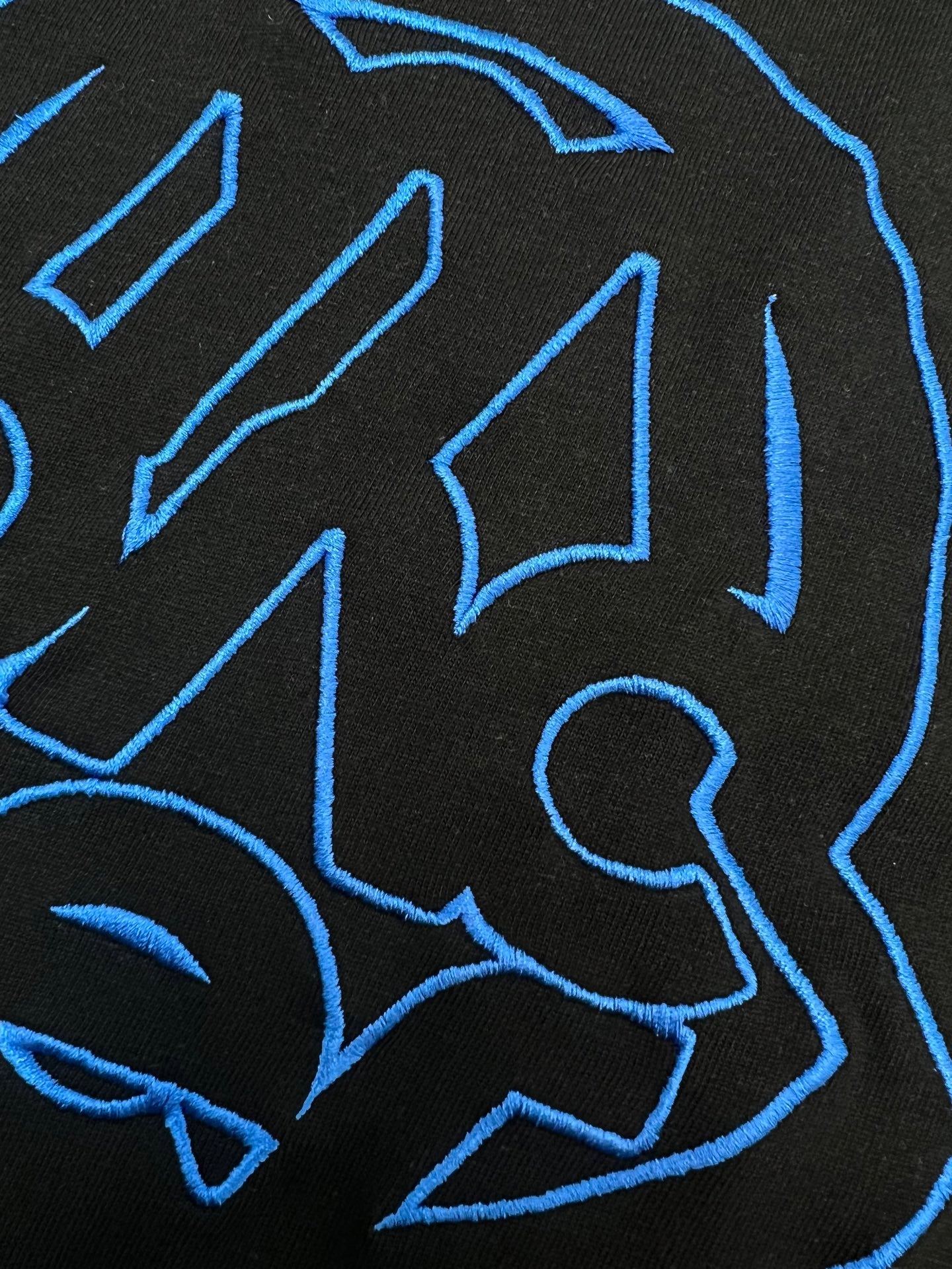 Black T-shirt close-up of blue outline logo graphic details