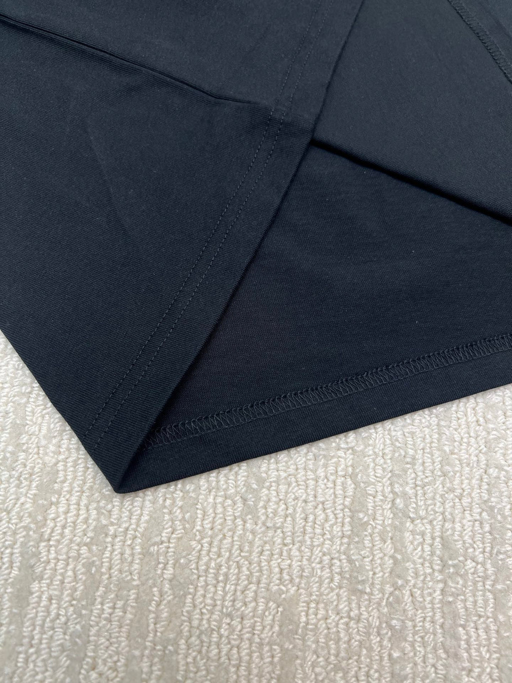 Black T-shirt neckline and hem seam close-up