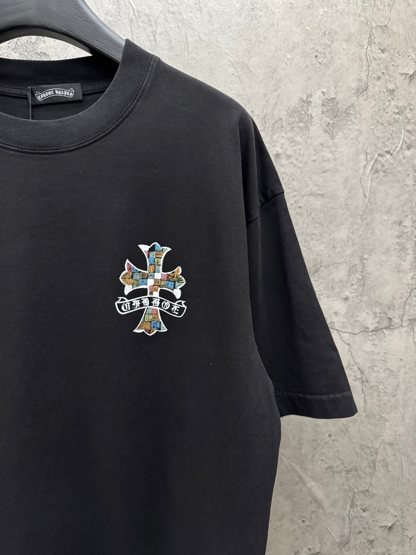 Black short-sleeve T-shirt with small multicolor cross chest graphic