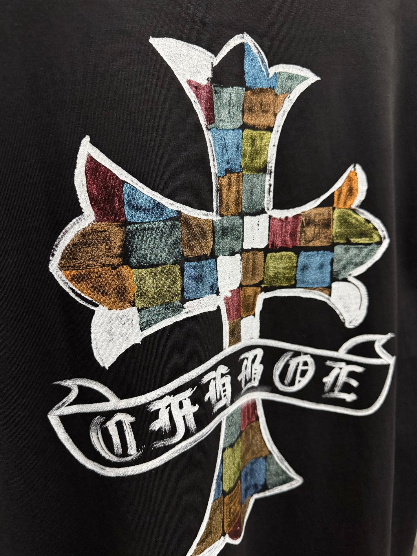 Black T-shirt back close-up of multicolor cross graphic and ribbon