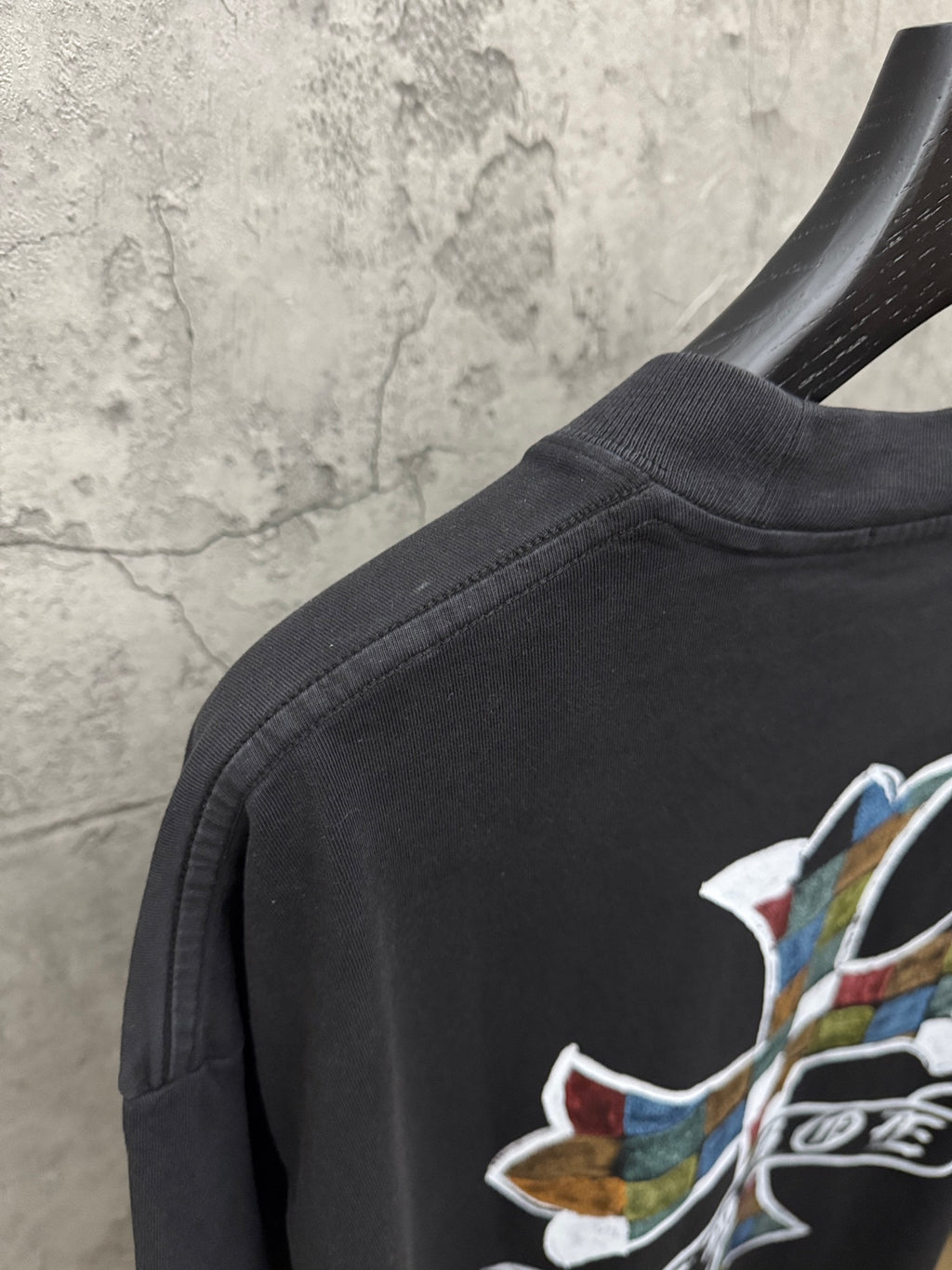 Black T-shirt shoulder area with partial multicolor cross graphic