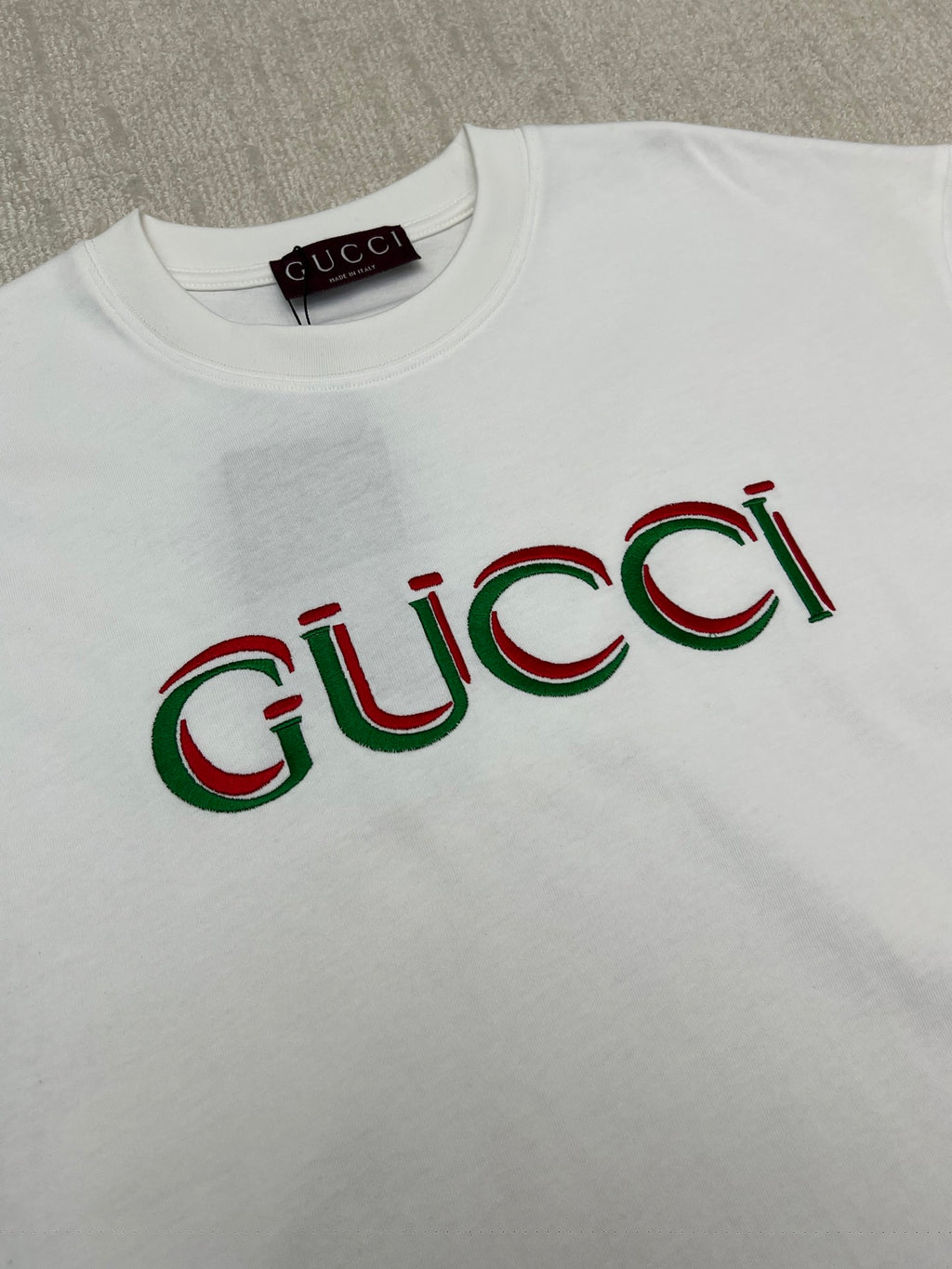 White Gucci T-shirt with multicolor Gucci logo print across the chest
