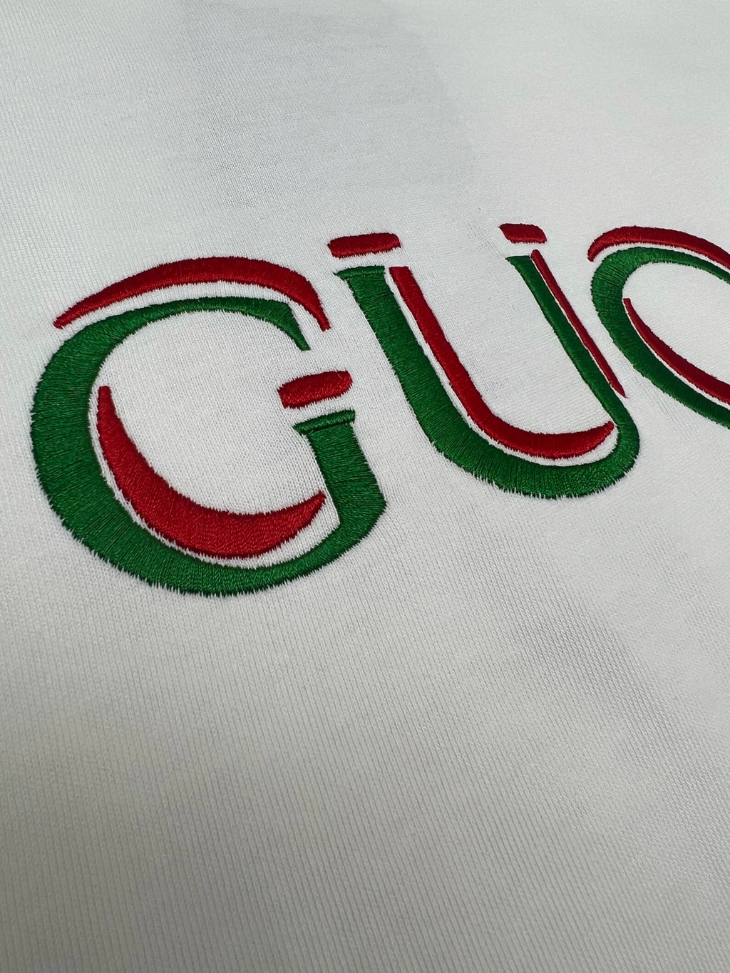 Close-up of white Gucci T-shirt with embroidered-style Gucci logo in red and green