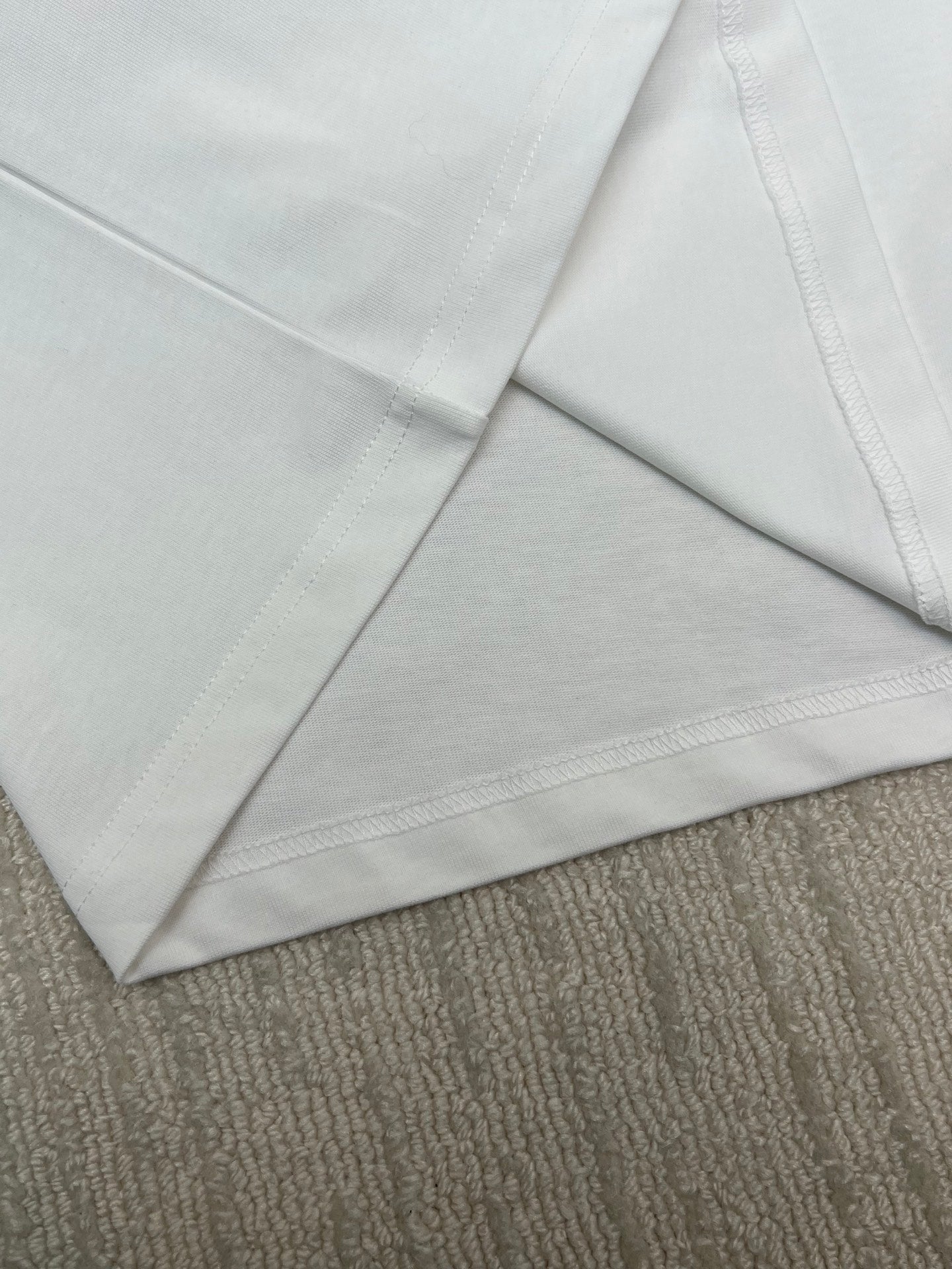 Close-up of white T-shirt with stitched sleeve and hem seams