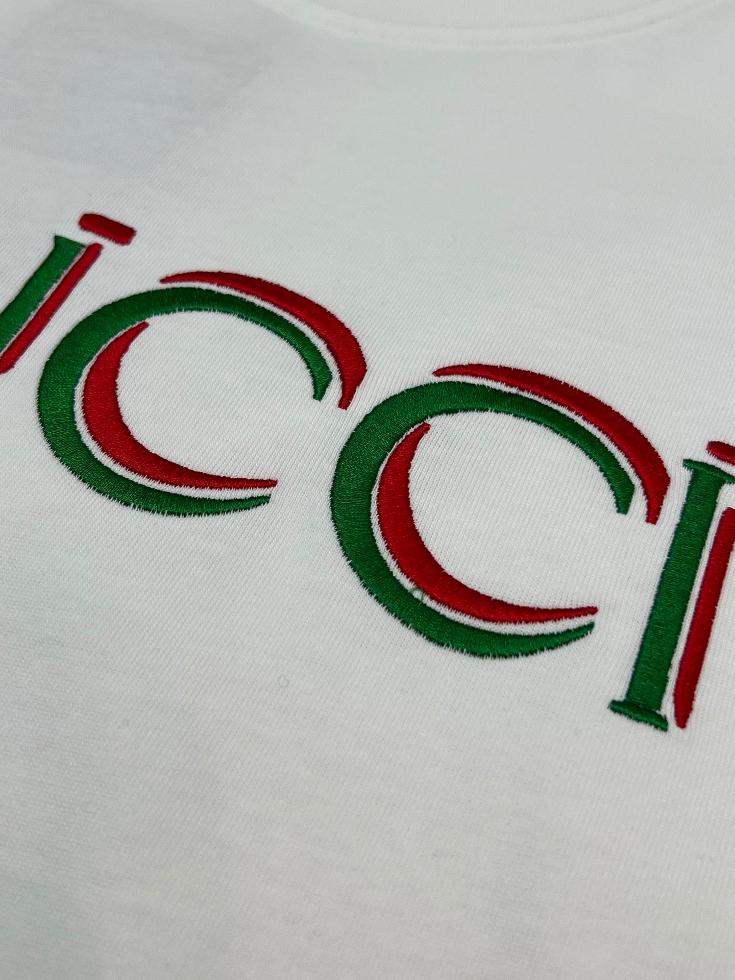 Close-up of white Gucci T-shirt with multicolor Gucci logo letters