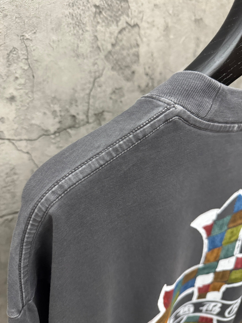 Dark gray T-shirt shoulder seam and neckline detail with partial cross graphic