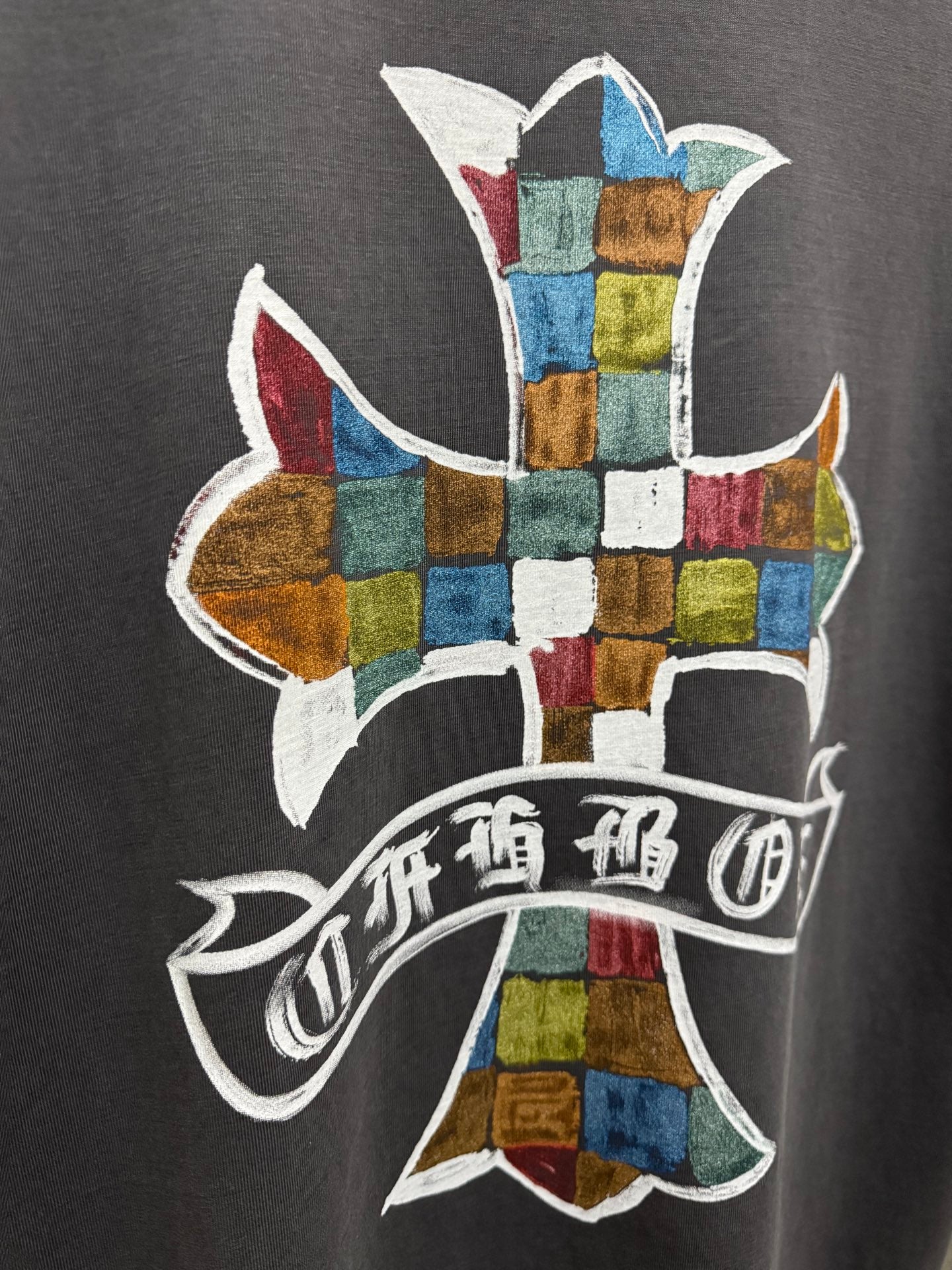 Close-up of multicolor cross graphic with ribbon text on dark gray T-shirt back