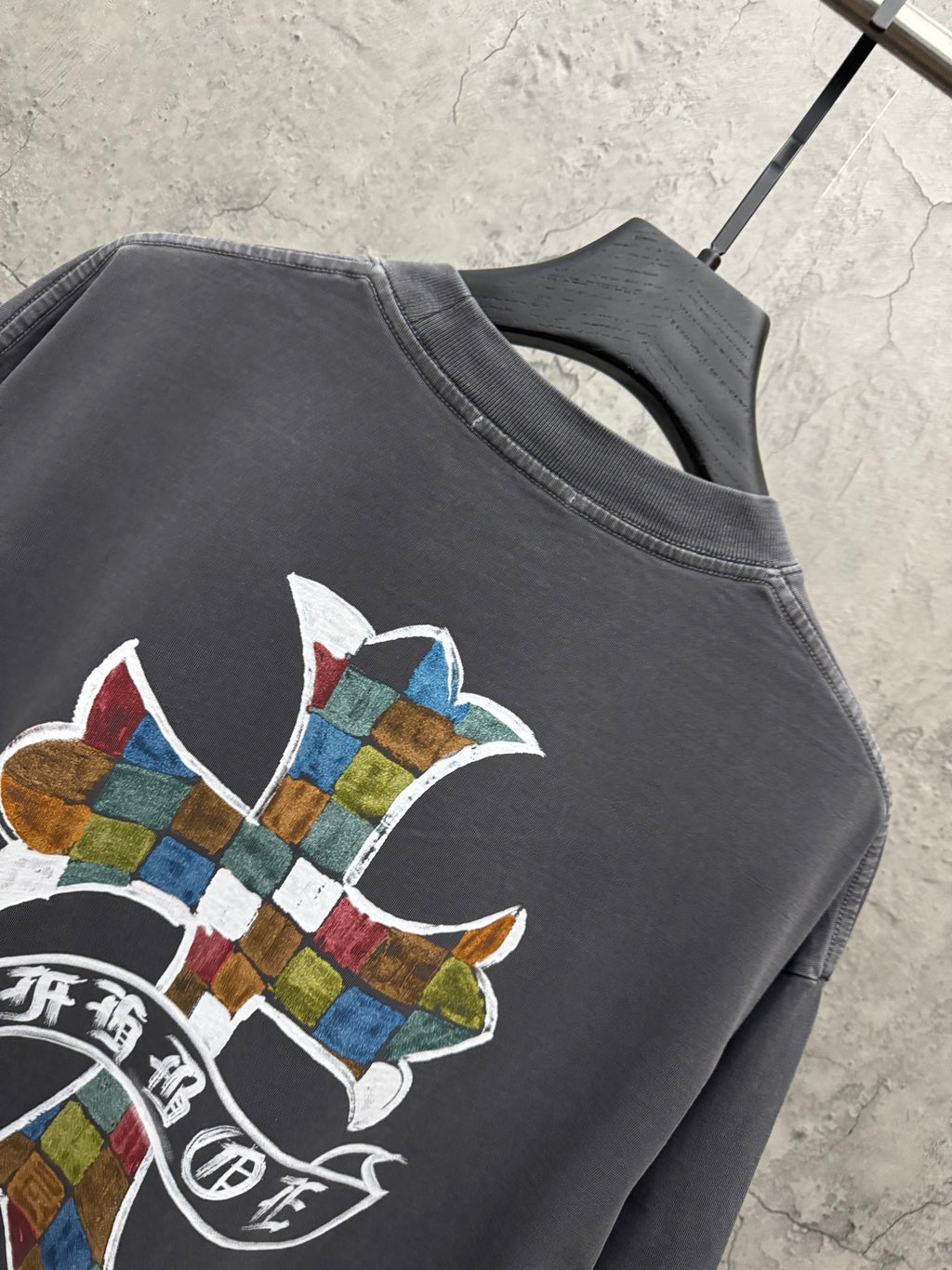 Dark gray short-sleeve T-shirt shoulder close-up with multicolor cross graphic and text