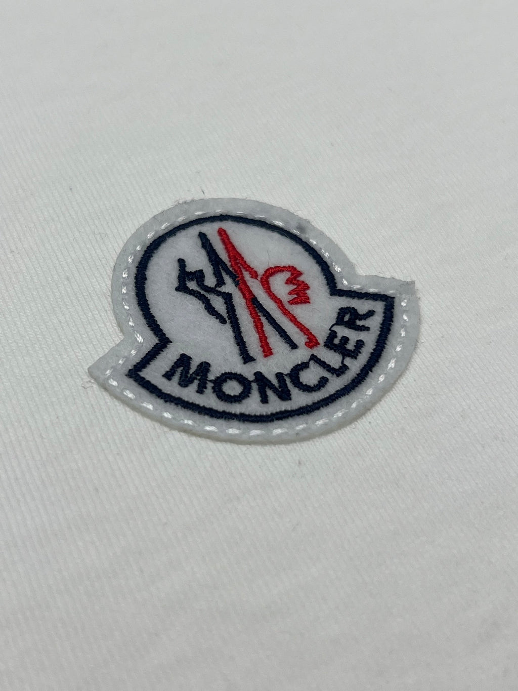 Close-up of Moncler round embroidered logo patch with red and black accents