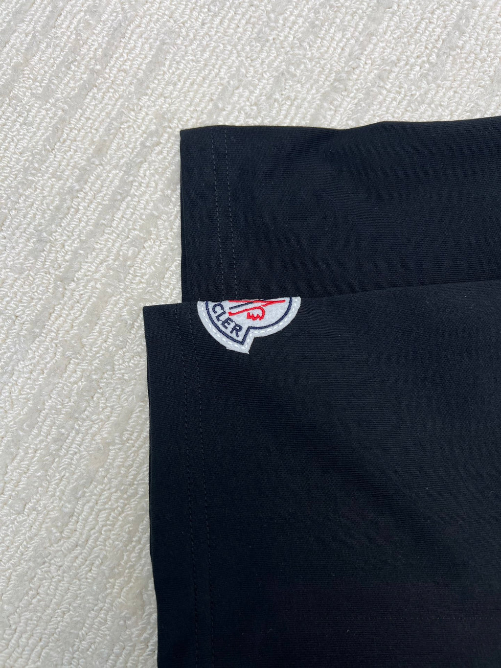 Back of black T-shirt with Moncler logo patch near collar