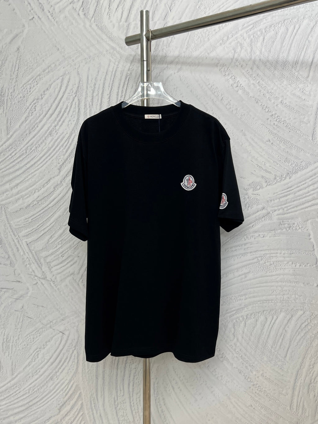 Black short-sleeve T-shirt with small round Moncler logo patch on chest