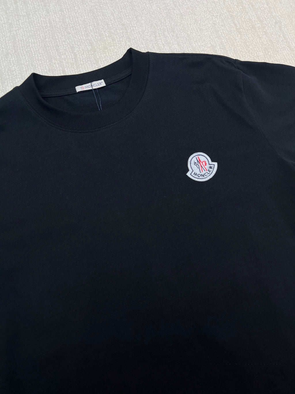 Black crew-neck T-shirt with round Moncler logo patch on chest