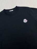 Black crew-neck T-shirt with round Moncler logo patch on chest