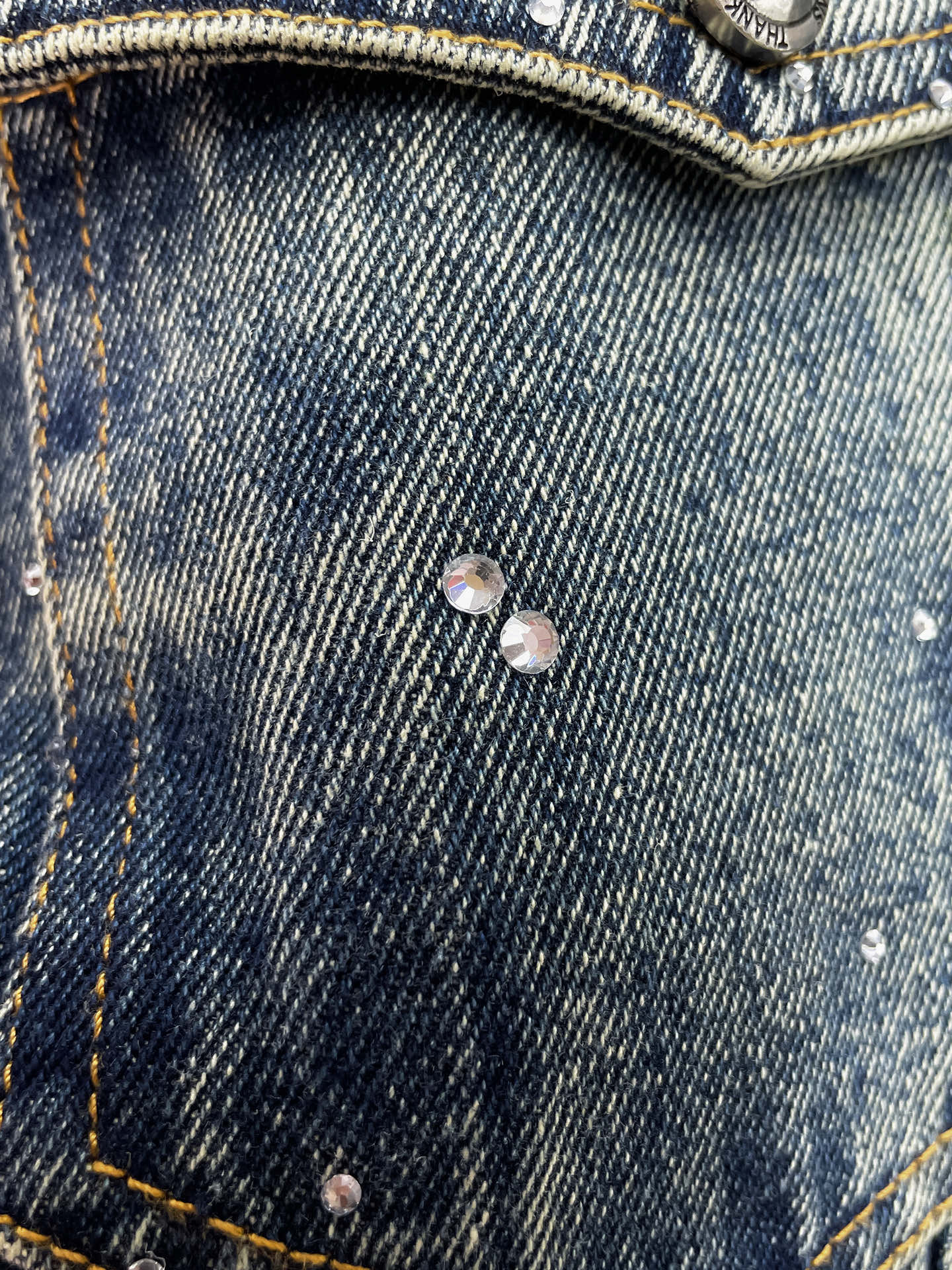 Denim jacket chest pocket with two metal buttons and speckled finish