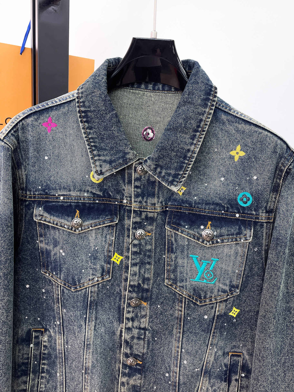 Denim jacket front with button chest pockets and colorful embroidered logo patches