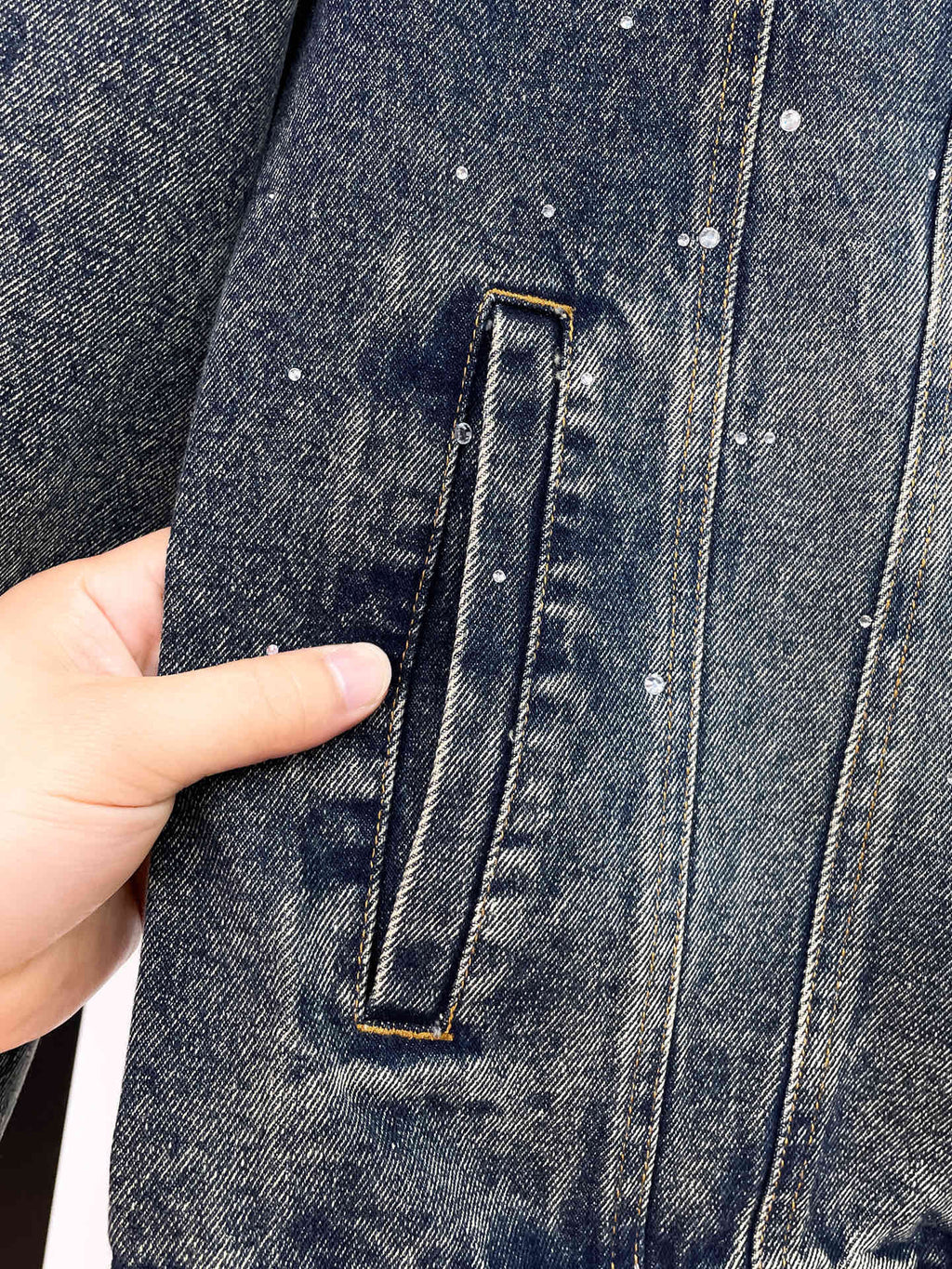 Denim jacket pocket detail with stitched rectangular flap and metal button
