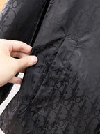 Dior hooded jacket, hand holding dark patterned fabric near side pocket seam