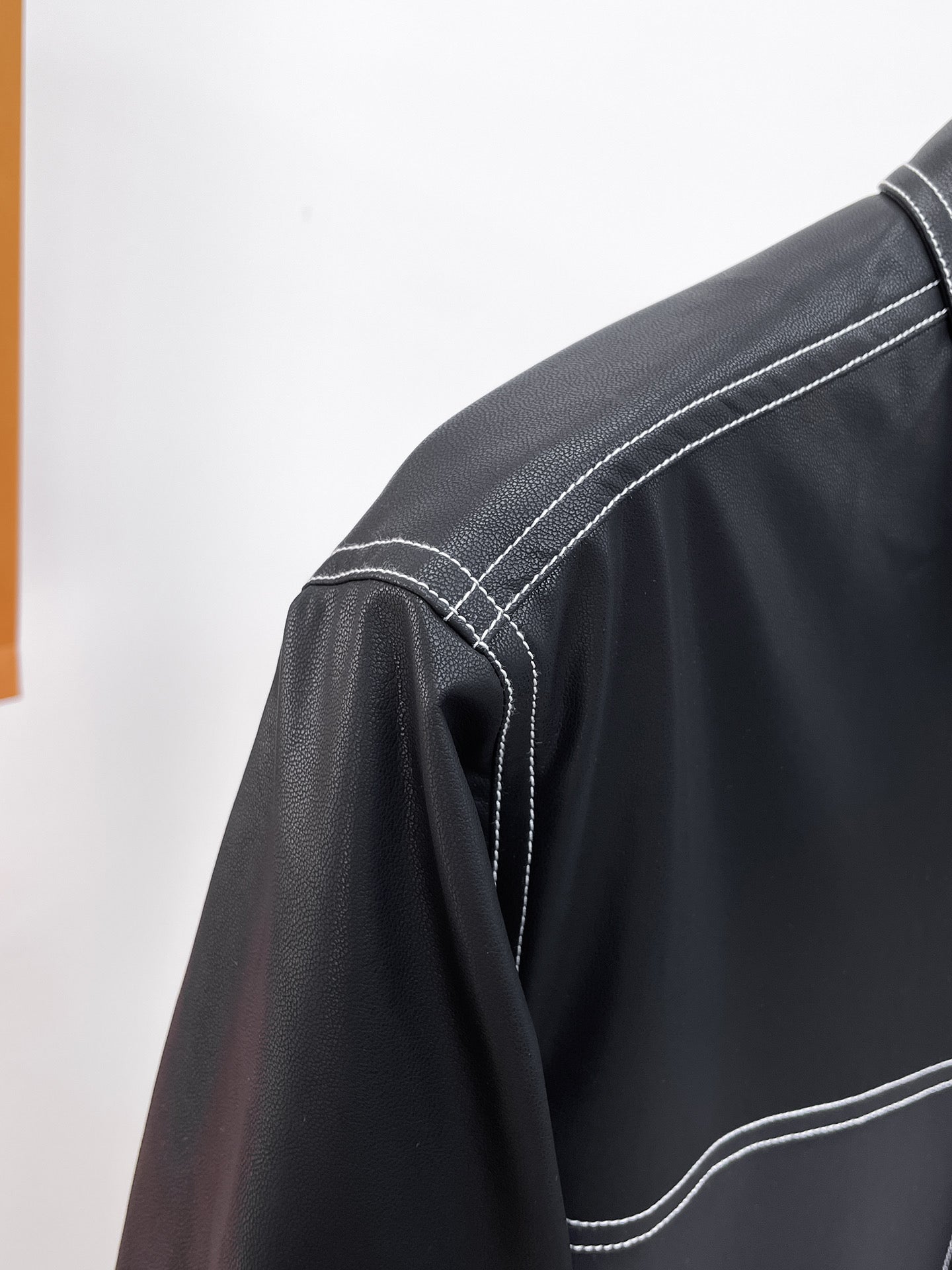 Black leather jacket sleeve with contrast topstitching and curved hem