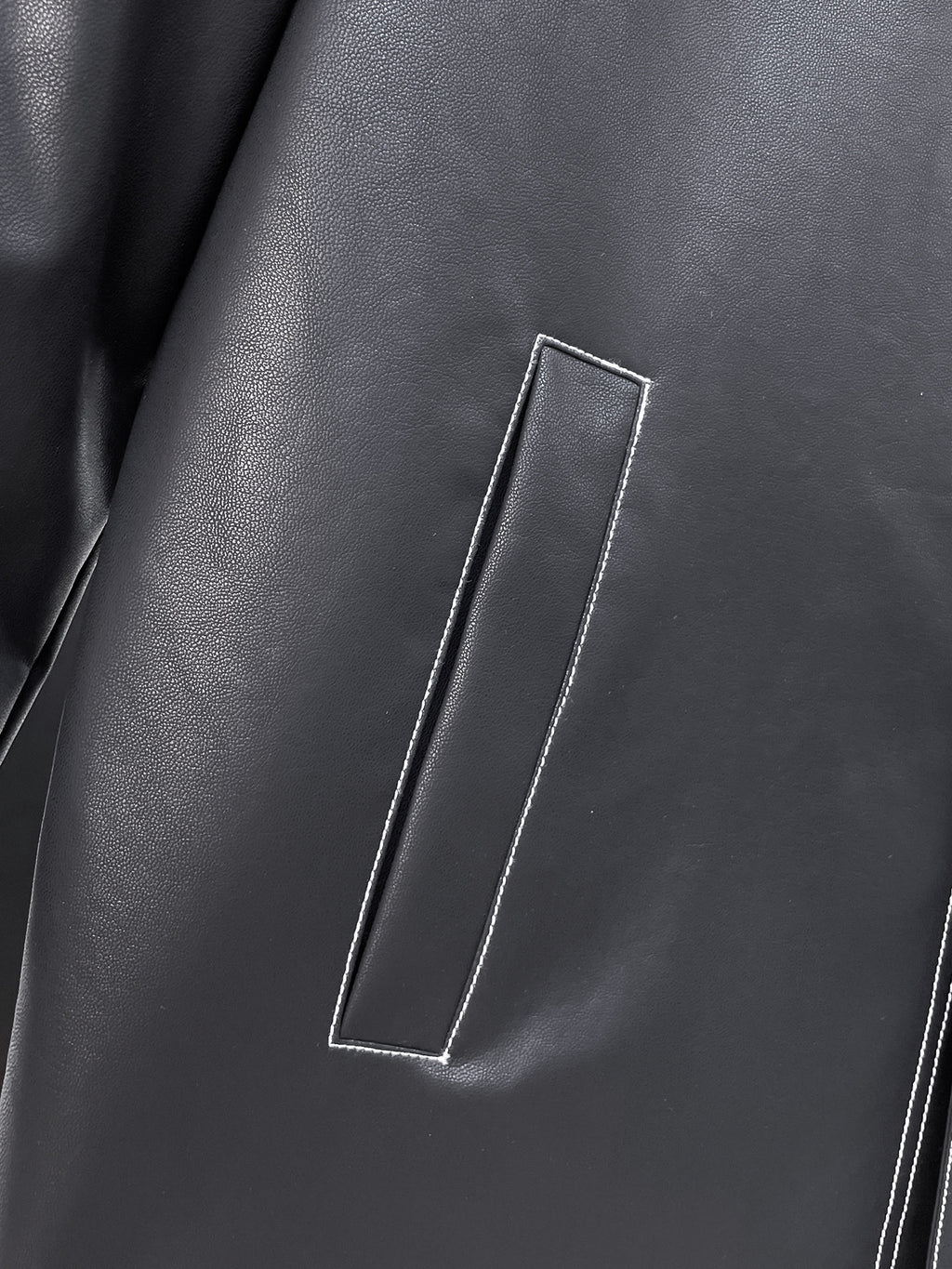 Black leather jacket front with vertical flap pocket and contrast piping