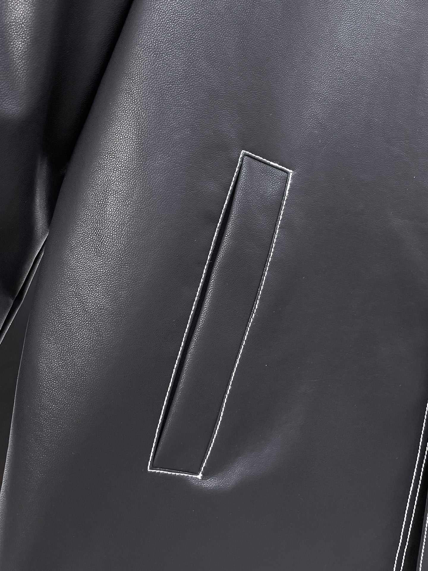 Black leather jacket front with vertical flap pocket and contrast piping