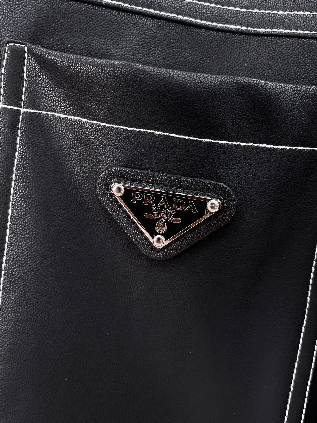 Prada logo patch on black leather chest pocket with contrast stitching
