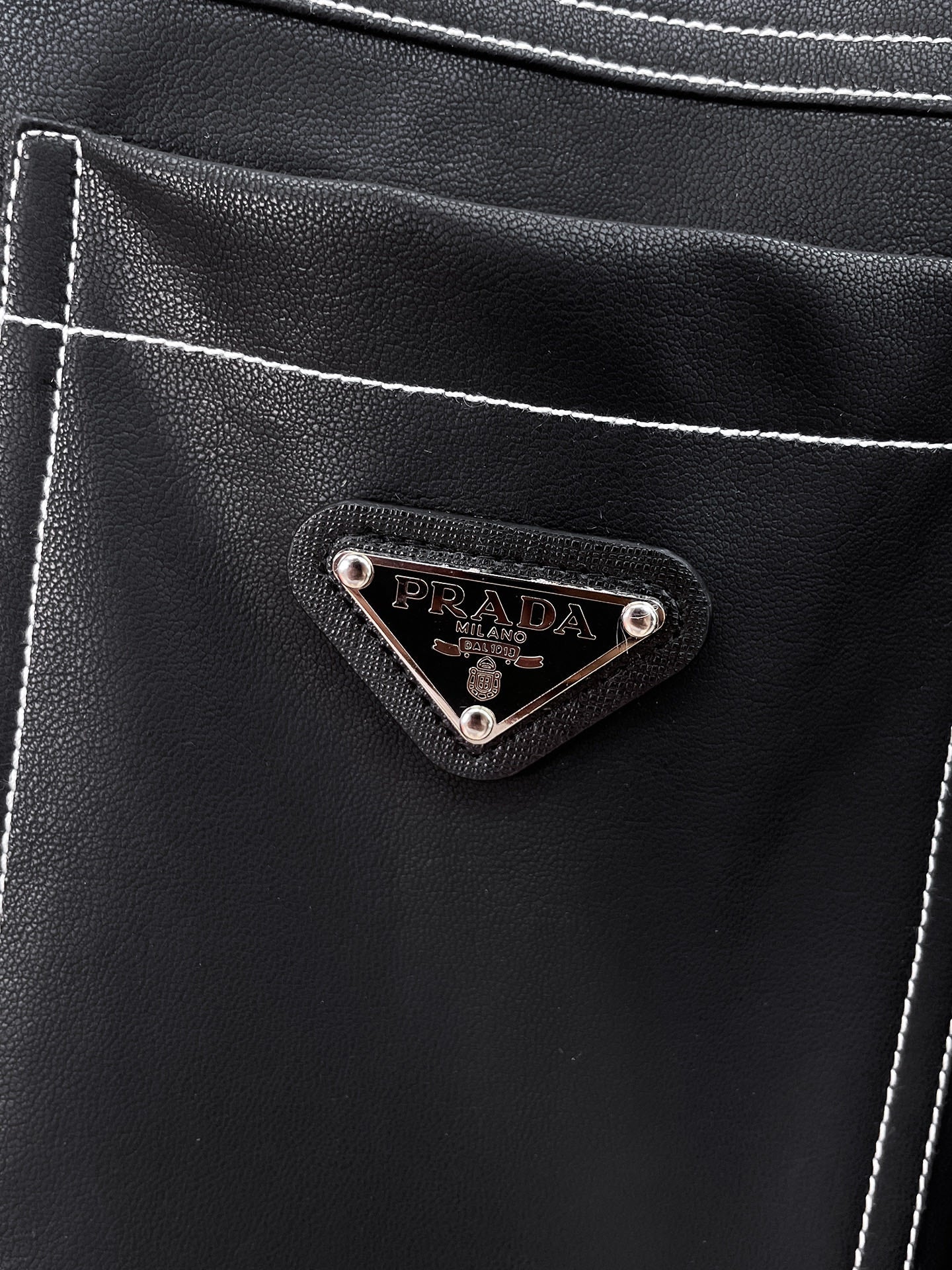 Prada logo patch on black leather chest pocket with contrast stitching
