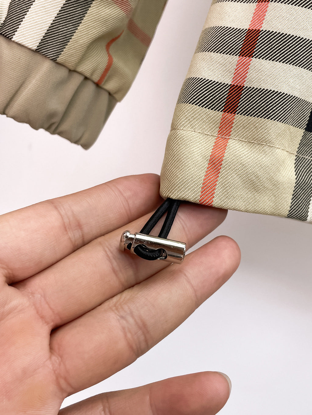 Zipper pull with small clip on plaid cuff fabric held in hand