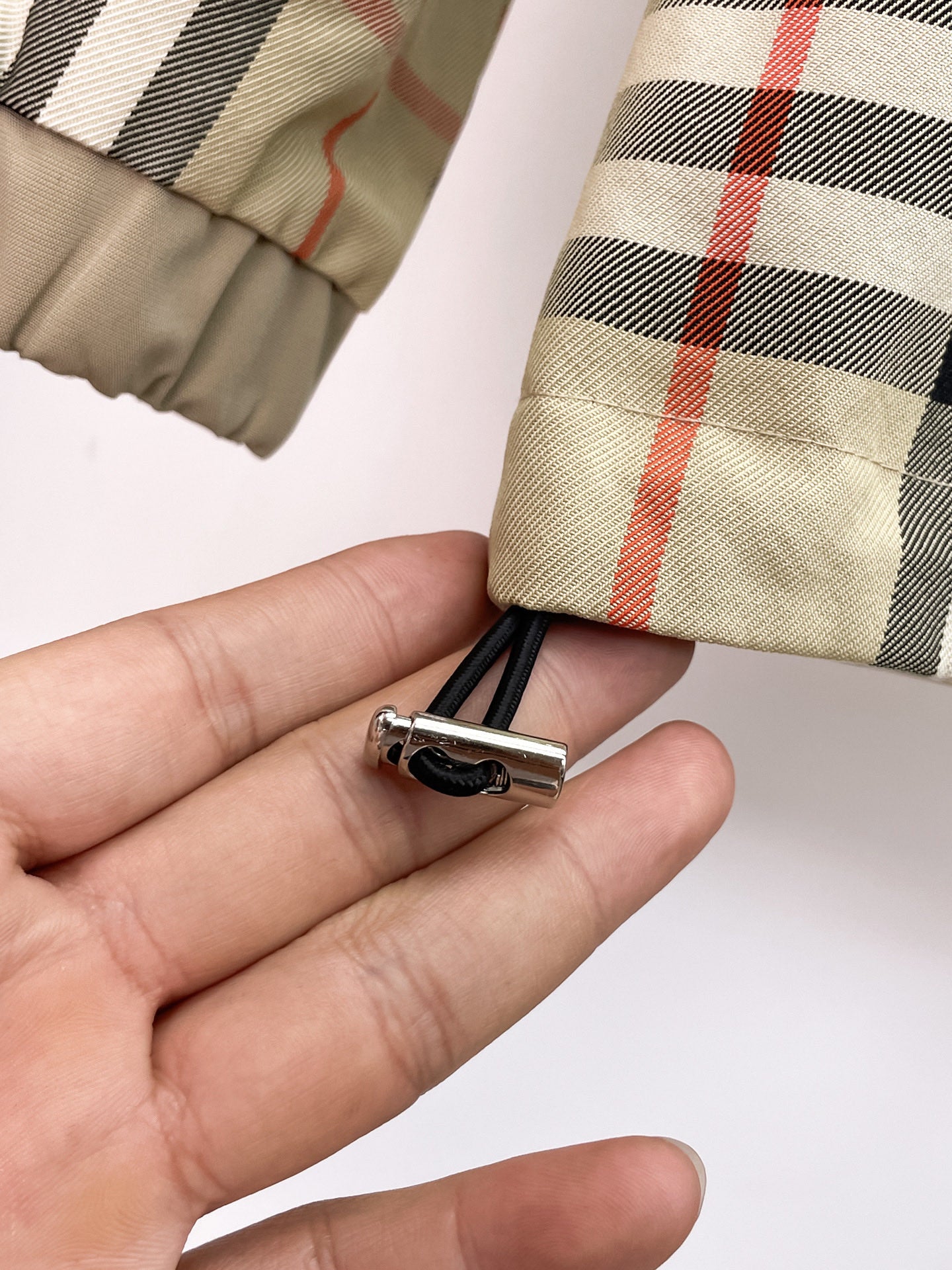 Zipper pull with small clip on plaid cuff fabric held in hand