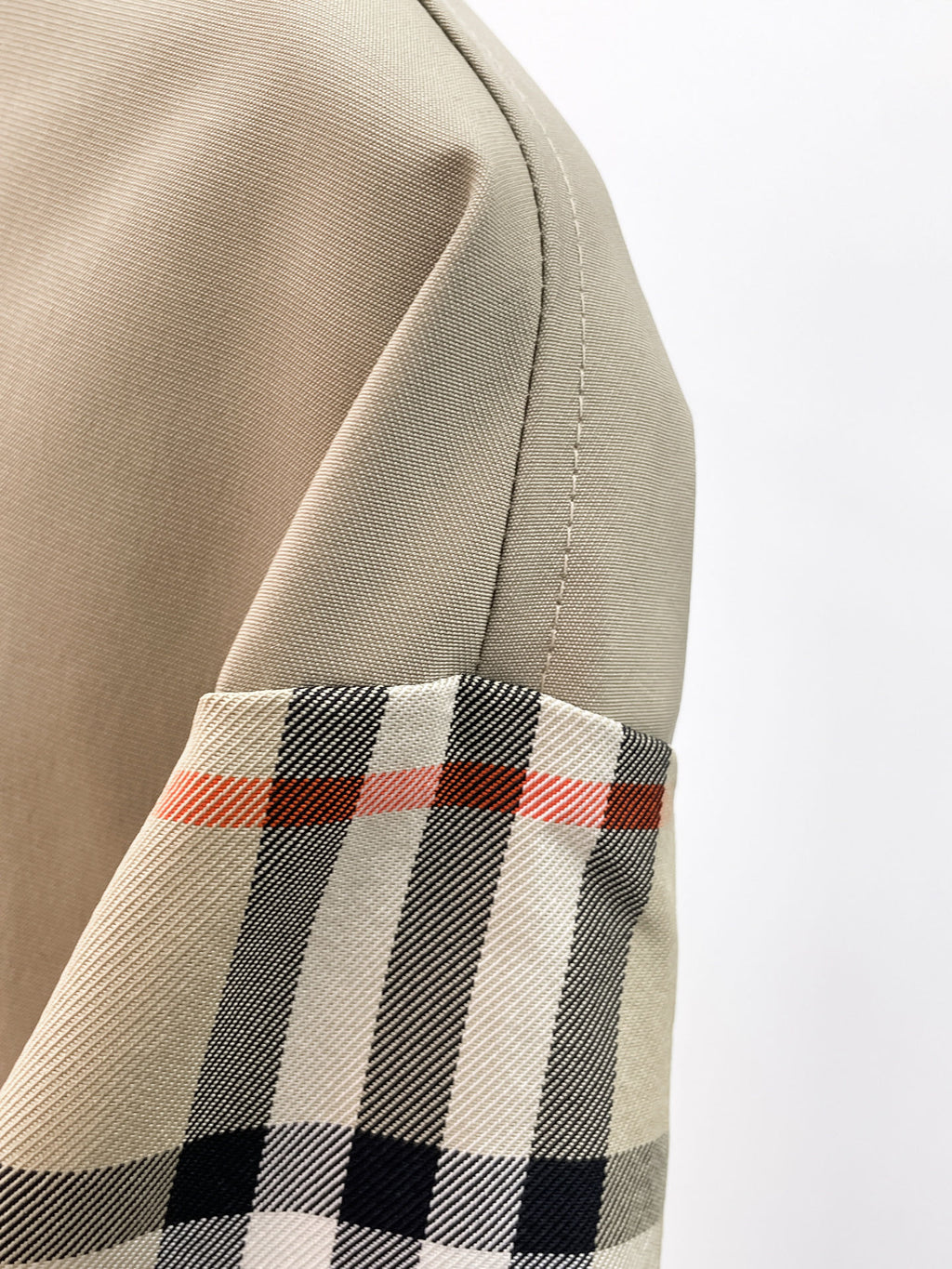 Beige jacket sleeve with black, white, and red plaid band at cuff