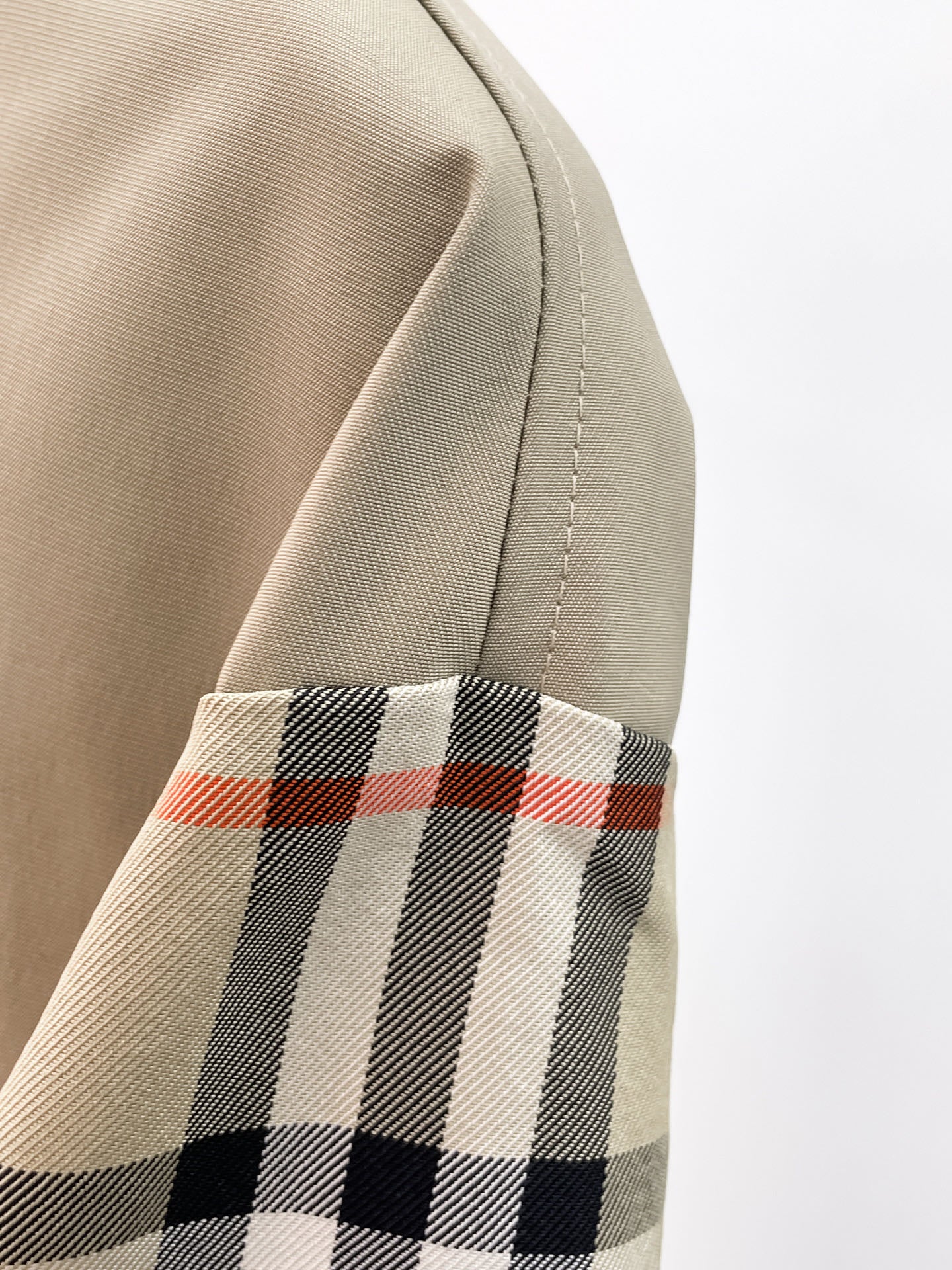 Beige jacket sleeve with black, white, and red plaid band at cuff