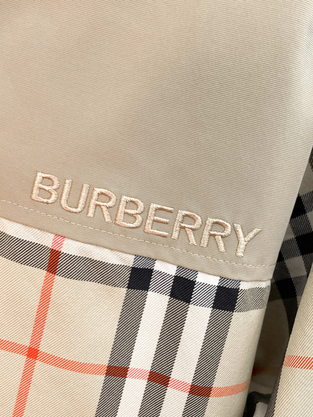 BURBERRY logo patch on beige fabric with black and red plaid trim