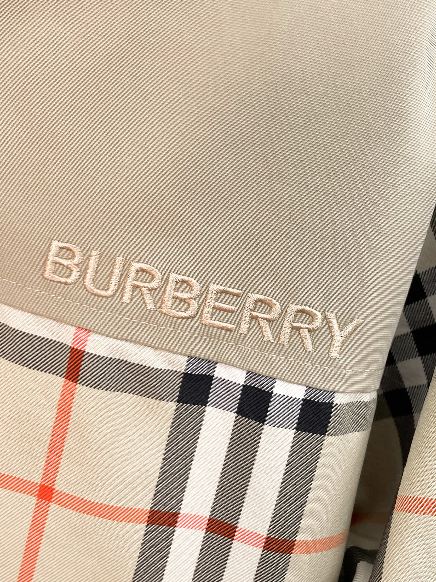 BURBERRY logo patch on beige fabric with black and red plaid trim