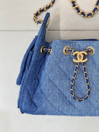 Chanel blue denim handbag detail: gold logo chain charm and side tassels