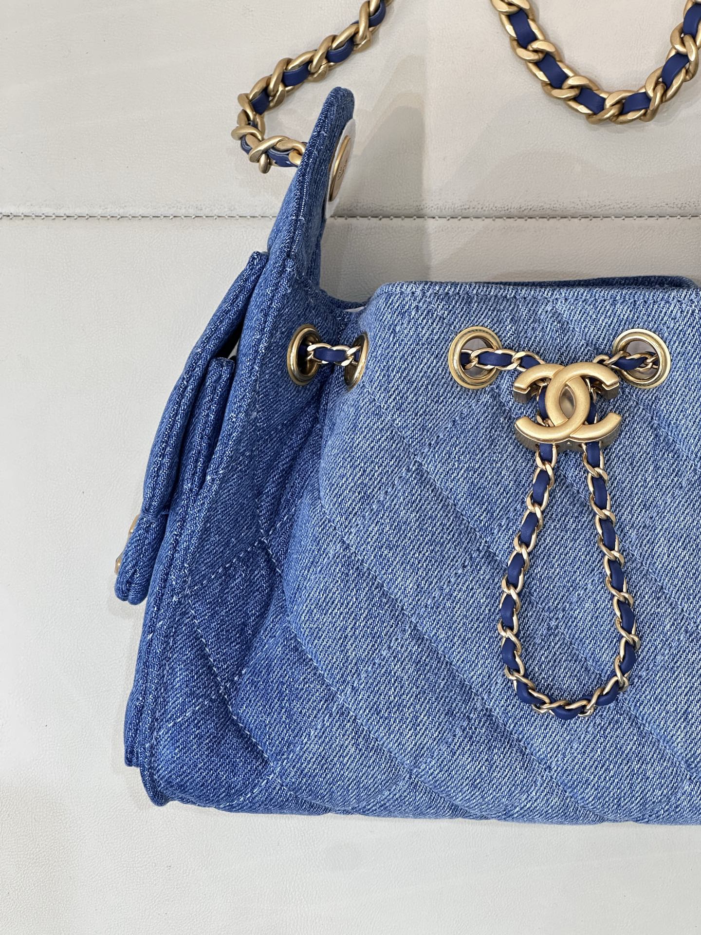 Chanel blue denim handbag detail: gold logo chain charm and side tassels