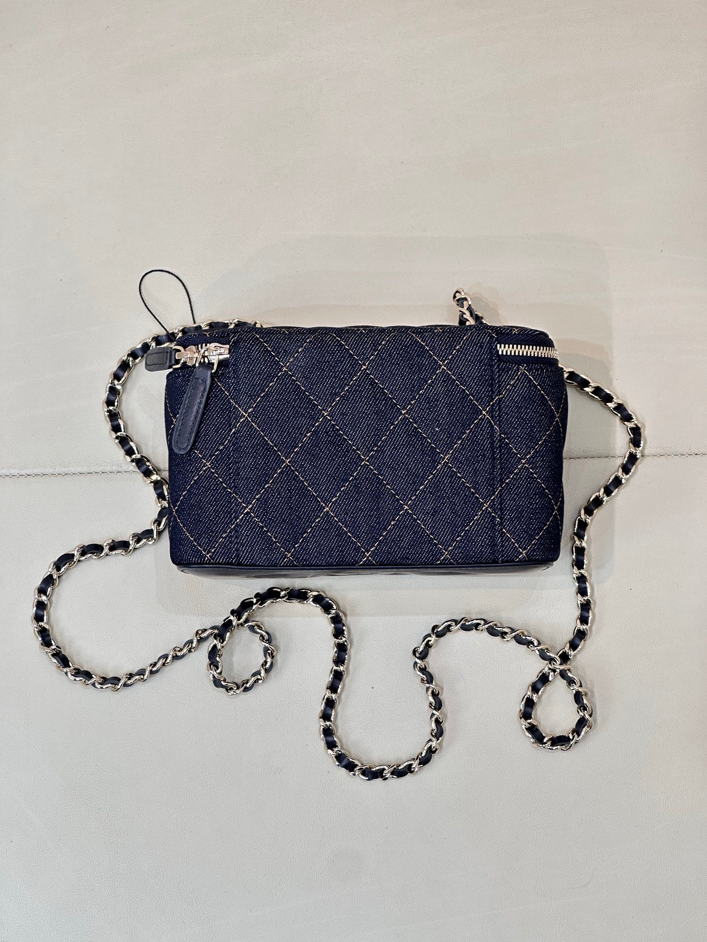 Chanel mini quilted bag in dark blue with chain strap and top zipper, angled view