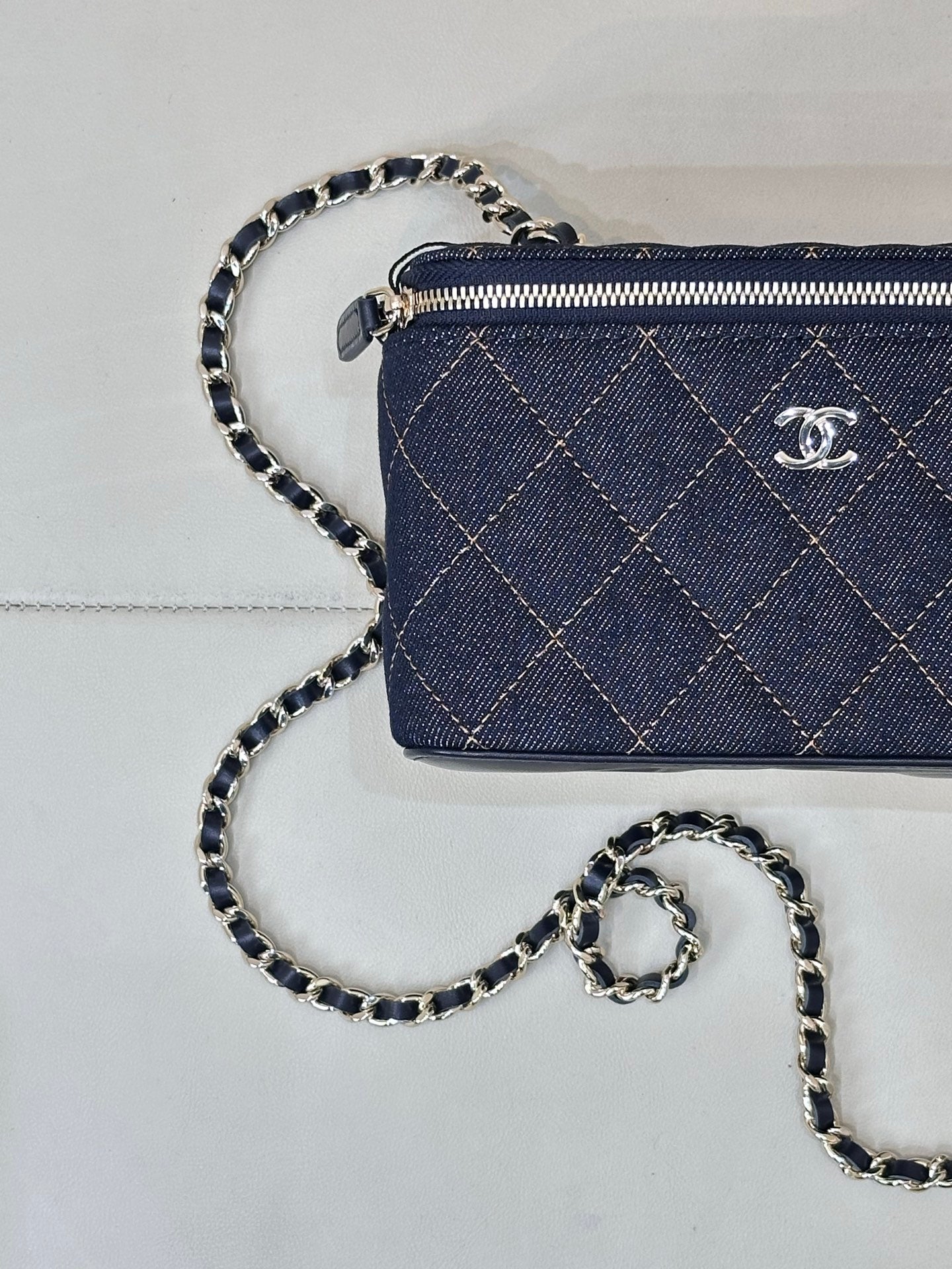 Chanel mini quilted bag in dark blue with top zip, CC emblem, and chain strap