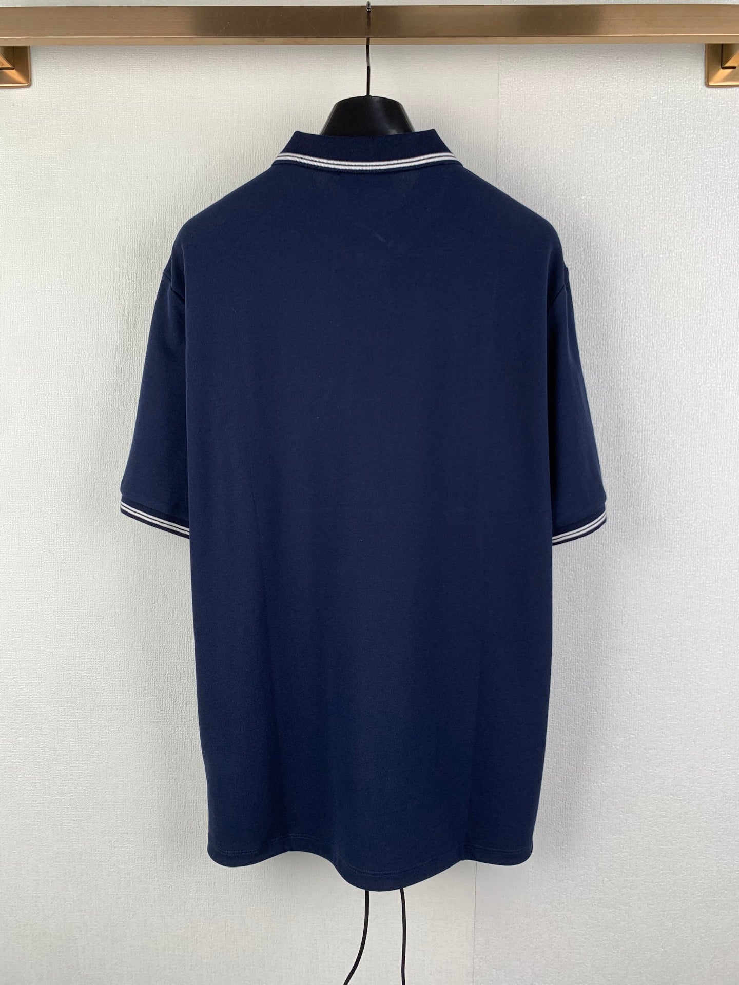 Navy polo shirt back view with white-trimmed collar and short sleeves
