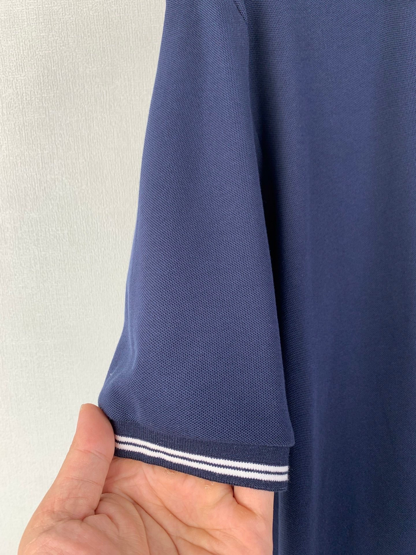 Navy polo shirt sleeve cuff with white and navy stripe trim